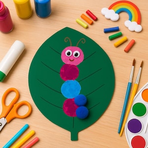 Puede incluir: Una manualidad en forma de hoja verde con un diseño de oruga rosa hecho de círculos y pompones. La imagen también incluye pintura, pinceles, tijeras, pegamento y un arcoíris, lo que sugiere un proyecto de manualidades para niños.