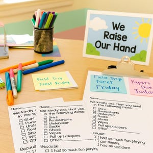 May include: A desk scene with school supplies and paperwork. A sign reads "We Raise Our Hand." There are checklists for items like shirts, pants, and wipes. Colorful markers and sticky notes are also visible.
