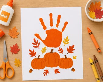 May include: A white sheet of paper featuring a central orange handprint above three orange pumpkins, surrounded by small red, orange, and yellow leaf illustrations. The paper is surrounded by a glue bottle, scissors, crayons, and paper leaves.