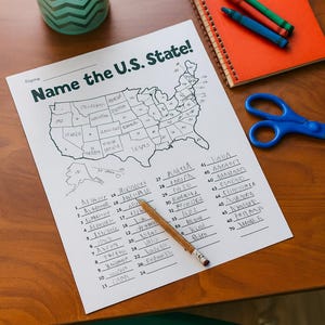May include: A worksheet titled "Name the U.S. State!" with a map outline and numbered lines for state names. A pencil rests on the paper, with a spiral notebook, crayons, and scissors nearby. A pencil holder with colored pencils is in the background.