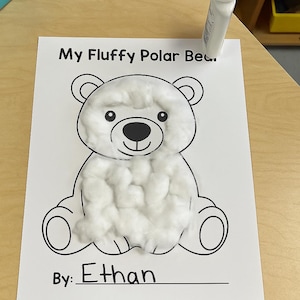 May include: A white paper craft project titled My Fluffy Polar Bear featuring a black and white line drawing of a bear with white cotton balls glued to the head and torso, with the name Ethan written below and a white glue bottle nearby.