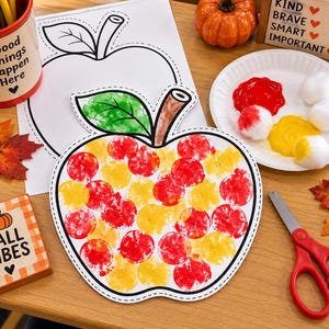 May include: A paper apple cutout decorated with red and yellow circular paint stamps, featuring a green leaf and brown stem. The craft project sits alongside a white paper plate with red and yellow paint, cotton balls, scissors, and a colouring sheet.