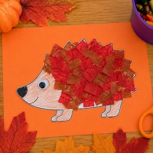 Könnte beinhalten: Ein Bastelprojekt auf orangefarbenem Papier mit einer Igel-Illustration, die ein Wackelauge und einen Körper aus kleinen, überlappenden roten und braunen Seidenpapierquadraten aufweist. Der Igel hat eine schwarze Nase und eine Handzeichnung.