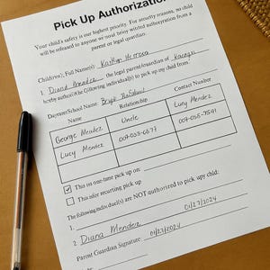 May include: A completed "Pick Up Authorization" form on a wooden surface, with a black pen to the left. The form includes fields for child's name, authorized individuals, and signatures. The date is 27/01/2024.
