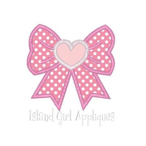 May include: A pink bow with white polka dots and a light pink heart in the center. The bow has a pink outline and the text "Island Girl Appliques" is below the bow.