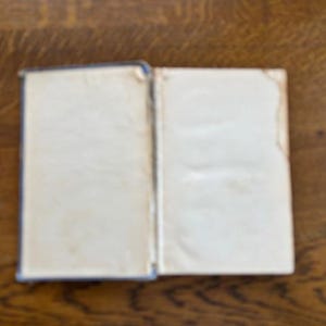 May include: A closed book with a white cover and blue edges. The book is lying open on a wooden surface.