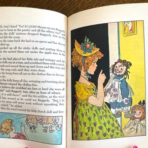 Puede incluir: Una ilustraci&oacute;n vintage de una ni&ntilde;a con cabello rojo y un vestido amarillo sosteniendo una mu&ntilde;eca de trapo. La mu&ntilde;eca de trapo lleva un vestido azul con un delantal blanco. La ni&ntilde;a est&aacute; se&ntilde;alando a la mu&ntilde;eca de trapo y diciendo "&iexcl;S&iacute;! &iexcl;Es mermelada!" La ilustraci&oacute;n es de un libro infantil.