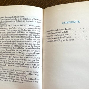 Puede incluir: Un libro titulado "Raggedy Ann" con una tabla de contenido que enumera los cap&iacute;tulos y los n&uacute;meros de p&aacute;gina. Los cap&iacute;tulos incluyen "Raggedy Ann aprende una lecci&oacute;n", "Raggedy Ann y la cometa", "Raggedy Ann rescata a Fido", "Raggedy Ann y el pintor", y "El viaje de Raggedy Ann por el r&iacute;o".
