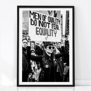 Op de afbeelding: Zwart-wit ingelijste print met een protestscène. Een bord met de tekst "MEN OF QUALITY DO NOT FEAR EQUALITY" wordt omhoog gehouden. De afbeelding legt een moment van solidariteit en activisme vast, met een menigte op de achtergrond.