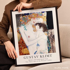 May include: A framed art print featuring Gustav Klimt's Mother and Child detail from The Three Ages of the Woman, 1905. The artwork depicts a pale woman with reddish hair holding a child, set against a dark background with gold accents.