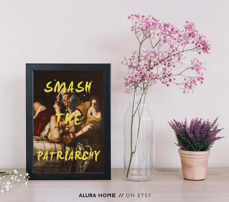 Puede incluir: Una impresi&oacute;n enmarcada en negro con una pintura de dos mujeres. La pintura es una reproducci&oacute;n de una obra de arte famosa. El texto "SMASH THE PATRIARCHY" est&aacute; escrito en pintura amarilla sobre la pintura.
