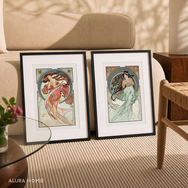 Puede incluir: Dos impresiones art&iacute;sticas enmarcadas con ilustraciones de estilo Art Nouveau de mujeres con cabello suelto y fondos ornamentados. Las impresiones tienen marcos negros y paspart&uacute;s blancos, con una paleta de colores de rojos, azules y verdes. Las impresiones se exhiben sobre una alfombra beige.