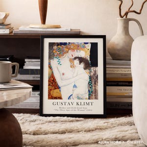May include: A framed art print featuring a detail from Gustav Klimt's painting Mother and Child from The Three Ages of the Woman. The print displays a woman with long red hair holding a child, with text below reading GUSTAV KLIMT Mother and Child detail from The Three Ages of the Woman (1905).