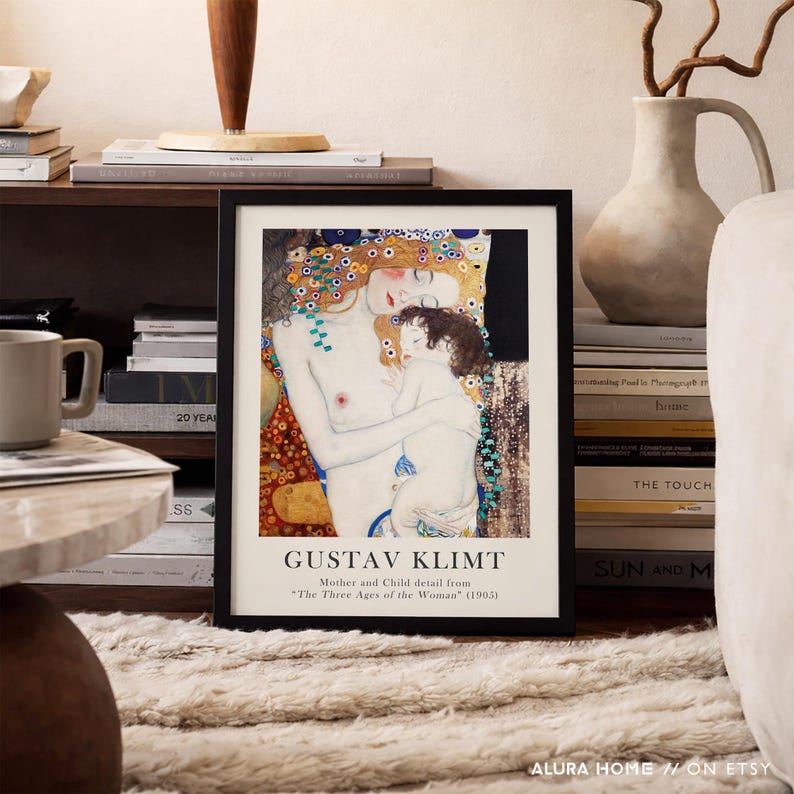 May include: A framed art print featuring a detail from Gustav Klimt's painting Mother and Child from The Three Ages of the Woman. The print displays a woman with long red hair holding a child, with text below reading GUSTAV KLIMT Mother and Child detail from The Three Ages of the Woman (1905).