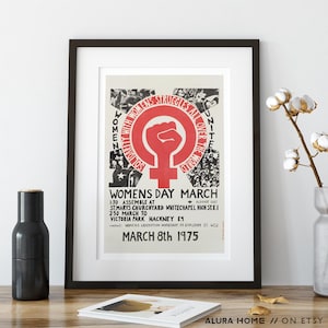 Puede incluir: P&oacute;ster enmarcado con borde negro. El p&oacute;ster presenta un pu&ntilde;o rojo dentro de un c&iacute;rculo con un s&iacute;mbolo femenino. El texto dice "WOMENS STRUGGLES ALL OVER THE WORLD" y "WOMENS DAY MARCH MARCH 8th 1975".