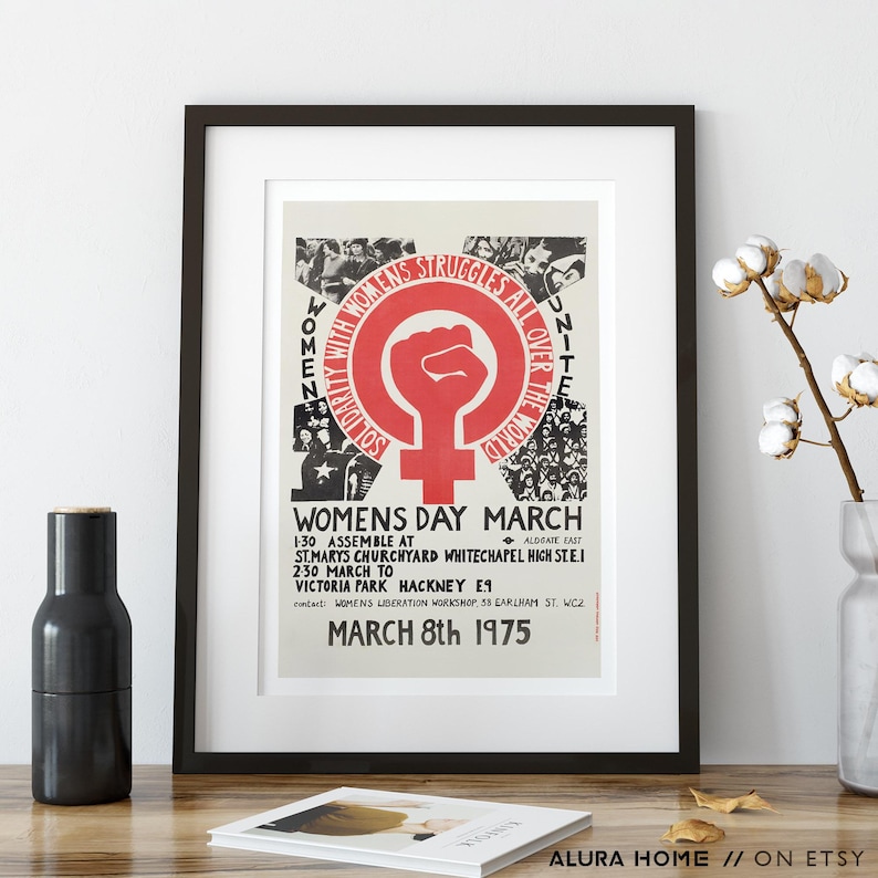 Puede incluir: P&oacute;ster enmarcado con borde negro. El p&oacute;ster presenta un pu&ntilde;o rojo dentro de un c&iacute;rculo con un s&iacute;mbolo femenino. El texto dice "WOMENS STRUGGLES ALL OVER THE WORLD" y "WOMENS DAY MARCH MARCH 8th 1975".
