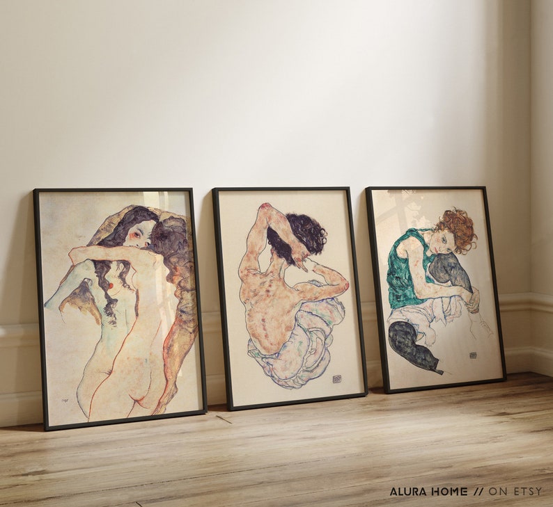 May include: Three framed black and white art prints of nude figures in various poses. The prints are set against a white wall.