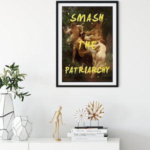 May include: A framed art print featuring a painting of a group of people in a woodland setting. The words "SMASH THE PATRIARCHY" are written in yellow paint across the image.