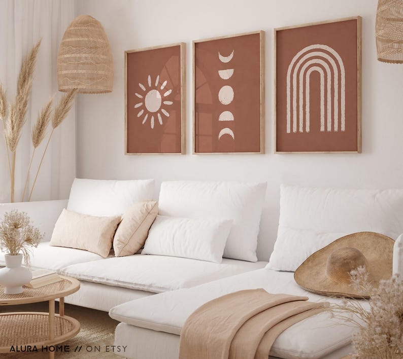 May include: Three framed wall art prints featuring a terracotta background with white line art illustrations. The left print shows a sun, the center print displays moon phases, and the right print depicts a rainbow arch. The text ALURA HOME // ON ETSY is visible.