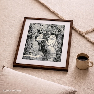 May include: A framed black and white illustration of mermaids in a forest setting. The artwork is in a dark brown wooden frame. A beige mug with coffee sits to the right of the frame. The image is on a beige rug.