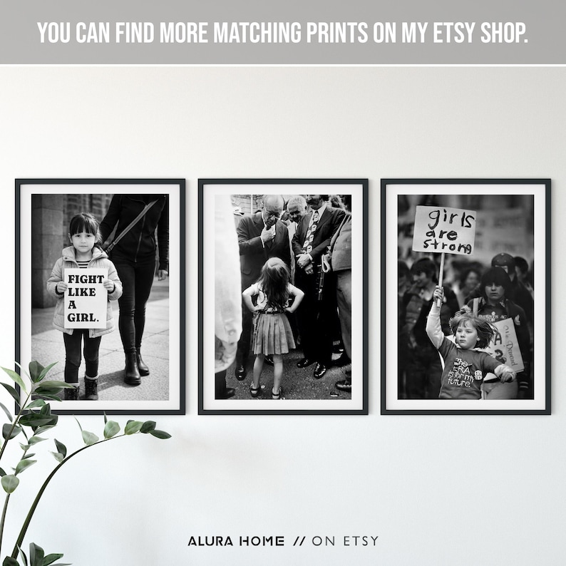 Peut inclure: Un triptyque de photographies encadr&eacute;es en noir et blanc. La premi&egrave;re montre une fille tenant une pancarte avec l'inscription "FIGHT LIKE A GIRL". La seconde montre une fille devant un groupe d'hommes. La troisi&egrave;me montre une fille tenant une pancarte avec l'inscription "girls are strong".