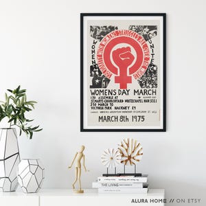 Puede incluir: Un p&oacute;ster enmarcado con borde negro, con un pu&ntilde;o rojo dentro de un c&iacute;rculo con un s&iacute;mbolo femenino. El texto dice "WOMENS STRUGGLES ALL OVER THE WORLD" y "WOMENS DAY MARCH MARCH 8th 1975".