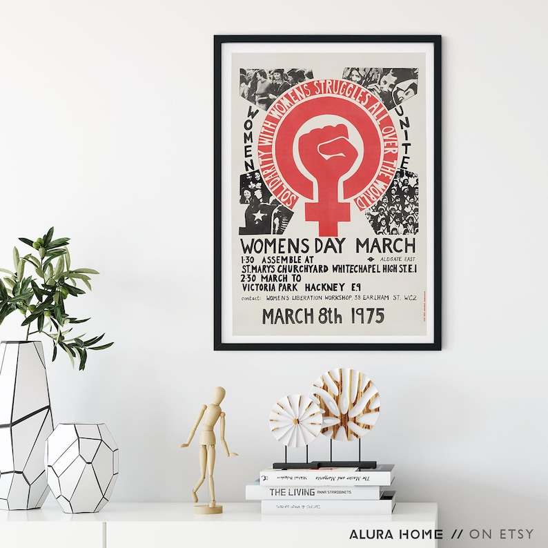 Puede incluir: Un p&oacute;ster enmarcado con borde negro, con un pu&ntilde;o rojo dentro de un c&iacute;rculo con un s&iacute;mbolo femenino. El texto dice "WOMENS STRUGGLES ALL OVER THE WORLD" y "WOMENS DAY MARCH MARCH 8th 1975".