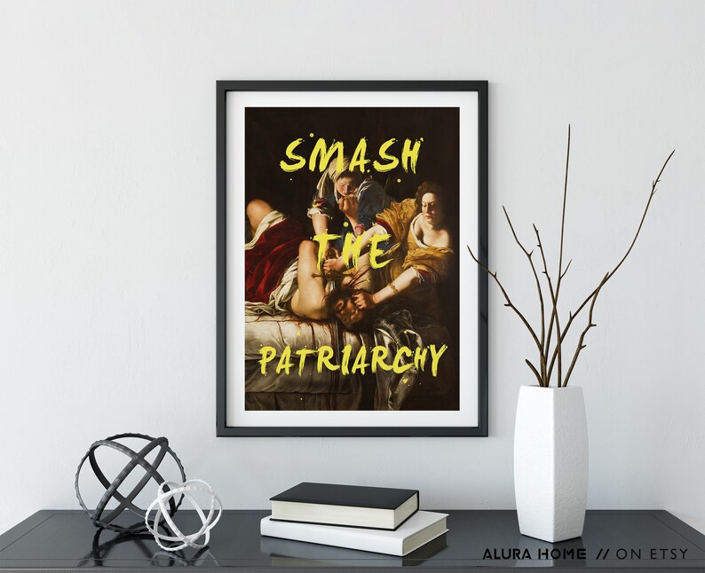 Puede incluir: Una impresi&oacute;n enmarcada en negro de una pintura que representa a tres figuras. Las figuras est&aacute;n en lucha, con una figura sujetando la cabeza de otra. La impresi&oacute;n tiene el texto "SMASH THE PATRIARCHY" en pintura amarilla.