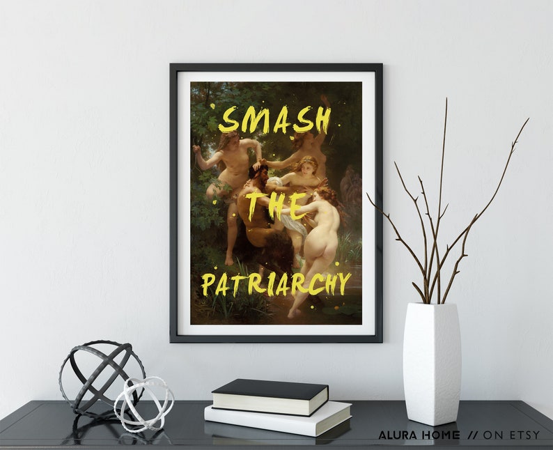 May include: A black framed print featuring a painting of a group of people in a woodland setting. The words "SMASH THE PATRIARCHY" are written in yellow paint across the image.