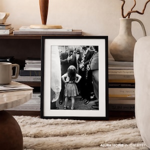 Peut inclure: Photographie en noir et blanc encadr&eacute;e, repr&eacute;sentant une jeune fille devant un groupe d'hommes en costume. La photo est expos&eacute;e sur une &eacute;tag&egrave;re avec des livres, une tasse et un vase d&eacute;coratif. L'image est de ALURA HOME // ON ETSY.