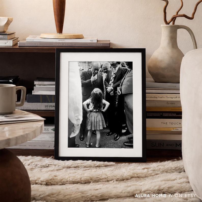 Peut inclure: Photographie en noir et blanc encadr&eacute;e, repr&eacute;sentant une jeune fille devant un groupe d'hommes en costume. La photo est expos&eacute;e sur une &eacute;tag&egrave;re avec des livres, une tasse et un vase d&eacute;coratif. L'image est de ALURA HOME // ON ETSY.