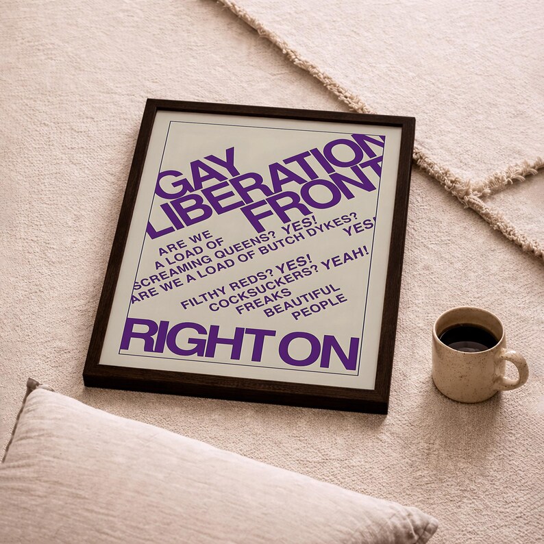 May include: A framed poster with a white background and purple text that reads: GAY LIBERATION FRONT, ARE WE A LOAD OF SCREAMING QUEENS? YES! ARE WE A LOAD OF BUTCH DYKES? YES! FILTHY REDS? YES! COCKSUCKERS? YEAH! FREAKS BEAUTIFUL PEOPLE RIGHT ON.
