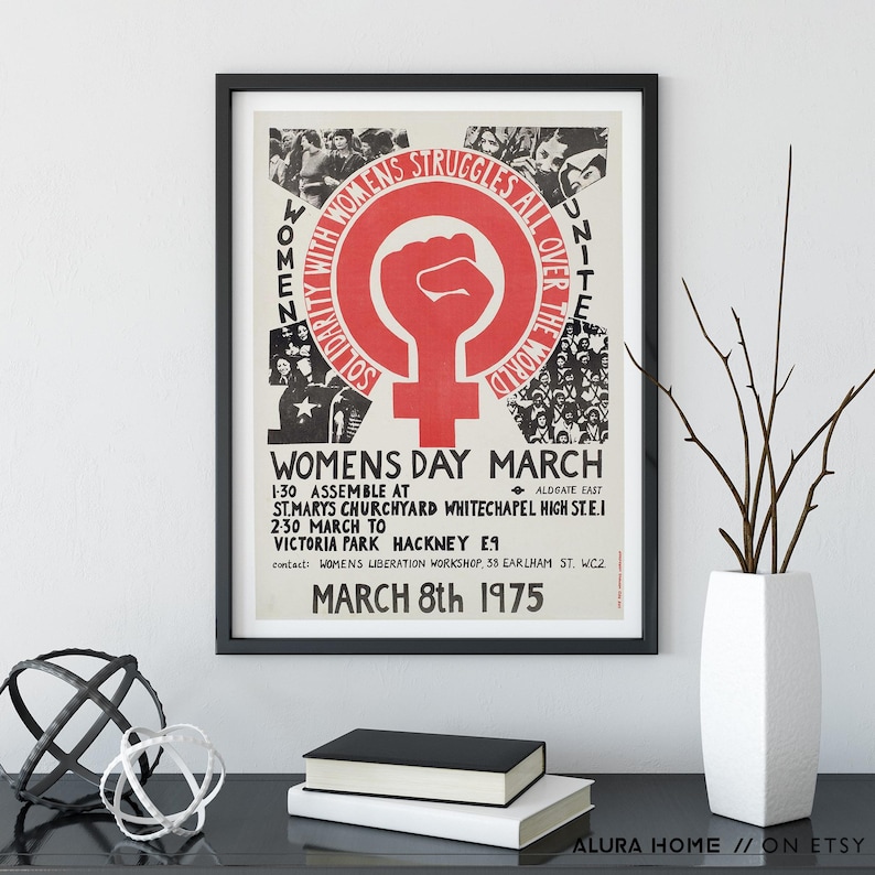 Puede incluir: Un p&oacute;ster enmarcado con borde negro. El p&oacute;ster tiene un dise&ntilde;o rojo y blanco con el texto "WOMENS DAY MARCH" y "SOLIDARITY WITH WOMEN'S STRUGGLES ALL OVER THE WORLD". Tambi&eacute;n es visible la fecha "MARCH 8th 1975".