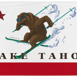 Op de afbeelding: Een witte vlag met een rode ster in de linkerbovenhoek. Een bruine beer met een skibril skiet een helling af met de tekst "SNO*CAL" op de ski's. De tekst "LAKE TAHOE" is in bruine letters onder de beer gedrukt. De onderkant van de vlag is rood.