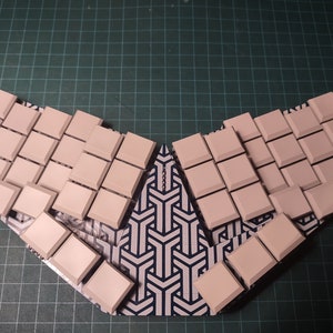 Puede incluir: Un conjunto de teclas de teclado blancas dispuestas en forma de V sobre una superficie con un patrón blanco y negro.