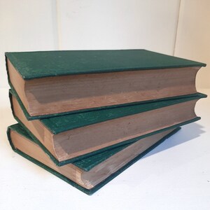 May include: Three hardcover books with green covers and brown spines stacked on top of each other.