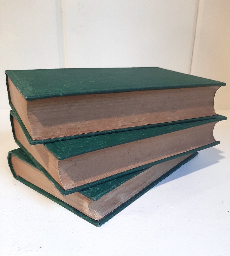 May include: Three hardcover books with green covers and brown spines stacked on top of each other.