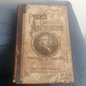 May include: A vintage book titled "Peck's Complete Arithmetic: Theoretical and Practical" by A.S. Barnes and Company. The cover features a portrait of Isaac Newton.