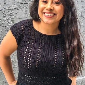 May include: A black crochet top with a delicate openwork pattern. The top has short sleeves and a round neckline. The model is wearing a bright green skirt.