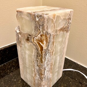 May include: A white and brown onyx lamp base with a natural, textured finish. The base is square and has a modern design.