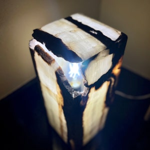 May include: A white onyx lamp with a natural wood base. The lamp is lit and the light shines through the onyx.