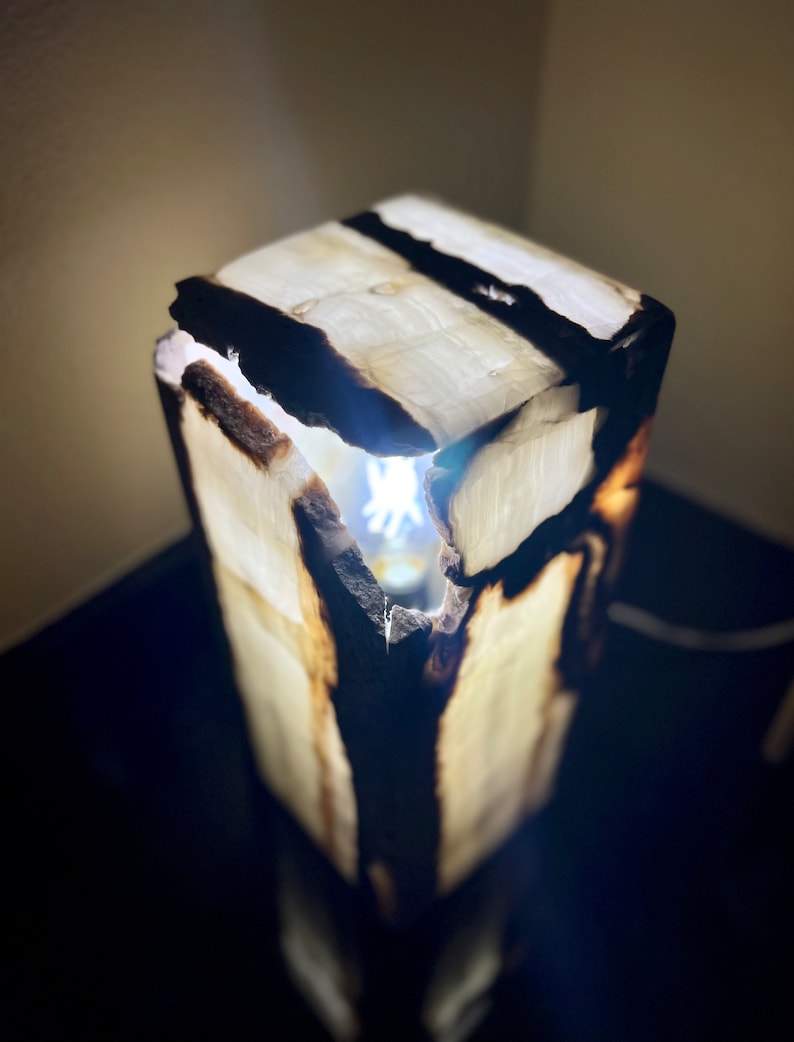 May include: A white onyx lamp with a natural wood base. The lamp is lit and the light shines through the onyx.