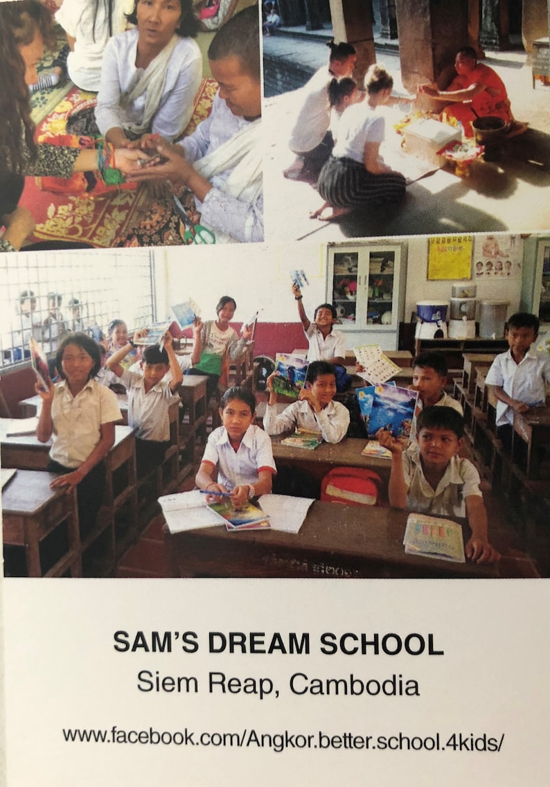 May include: A group of children in a classroom setting, some holding books and others looking at the camera. The classroom is brightly lit and has a water cooler and a sign that reads "Sam's Dream School, Siem Reap, Cambodia".