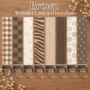 May include: Eight wristlet lanyard keychains featuring various brown and beige patterns including gingham, checkerboard, floral, zebra stripes, concentric lines, vertical stripes, bows, and small flowers, each attached to a silver metal ring.