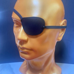 Op de afbeelding: Een zwart ooglapje met een verstelbare elastische band. Het ooglapje is gemaakt van zacht, comfortabel materiaal en is ontworpen om één oog te bedekken.