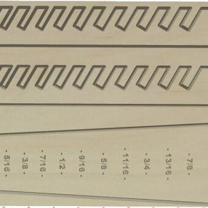 May include: A wooden board with a series of slots cut into it, labeled with fractions of an inch, from 1/4 inch to 7/8 inch. This board is likely used for woodworking or crafts.