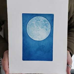 May include: A blue and white print of a full moon on a white background.