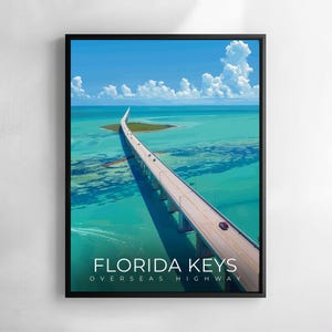 Può includere: Stampa artistica incorniciata raffigurante la Florida Keys Overseas Highway. L'immagine mostra un lungo ponte sull'acqua turchese sotto un cielo blu con nuvole bianche. Le parole "Florida Keys" sono stampate in basso.