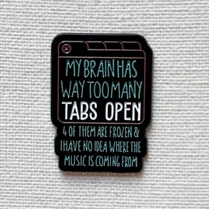 Può includere: Spilla in smalto nero con contorno bianco che rappresenta una finestra del browser con più schede aperte. Il testo recita "Il mio cervello ha troppe schede aperte. 4 di esse sono bloccate e non ho idea da dove provenga la musica."