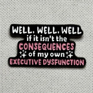 Peut inclure: Épinglette en émail noir avec du texte blanc qui dit "WELL, WELL, WELL if it isn't the CONSEQUENCES of my own EXECUTIVE DYSFUNCTION". Le texte "CONSEQUENCES" est en rose.